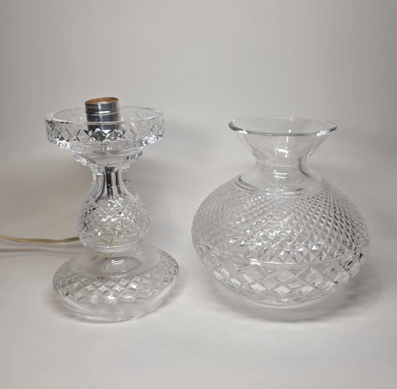 May include: Two clear glass objects with diamond-cut patterns. One is a lamp base with a silver socket and a power cord. The other is a round vase. Both are on a white background.