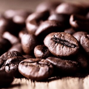 Può includere: Primissimo piano di chicchi di caffè tostati, che mostrano il loro ricco colore marrone e le loro forme irregolari.