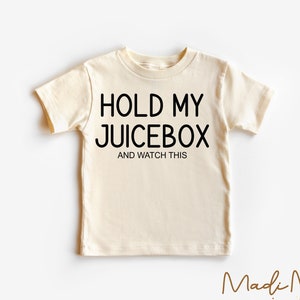 K&ouml;nnte beinhalten: Ein cremefarbenes T-Shirt mit schwarzem Text, der "Hold My Juicebox and Watch This" lautet.