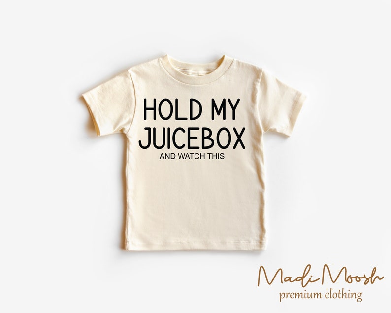 K&ouml;nnte beinhalten: Ein cremefarbenes T-Shirt mit schwarzem Text, der "Hold My Juicebox and Watch This" lautet.