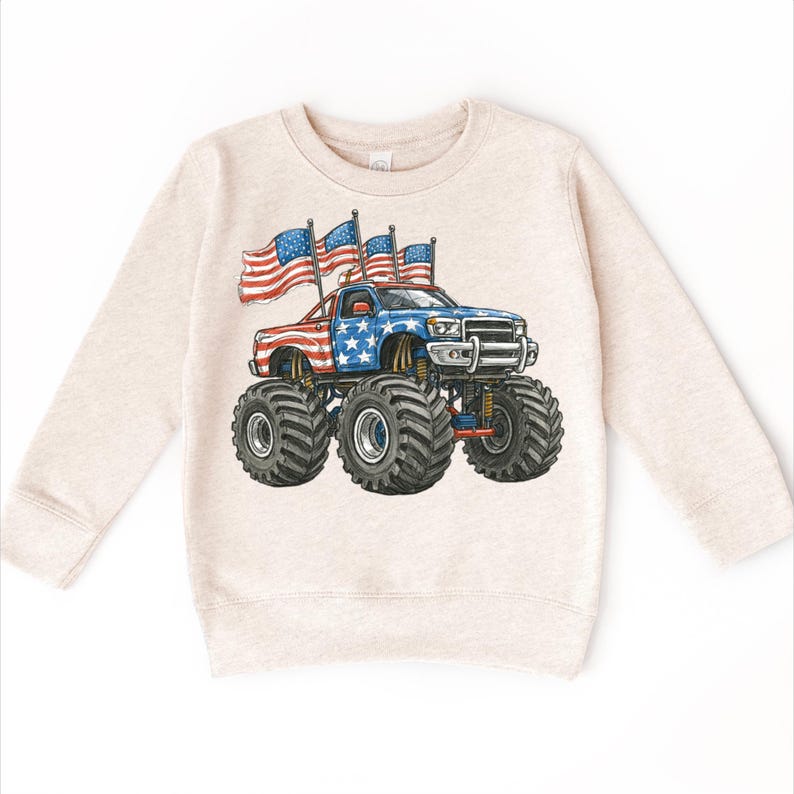 Pode incluir: Camisola bege com um gr&aacute;fico de um monster truck decorado com a bandeira americana. O cami&atilde;o tem pneus grandes e &eacute; adornado com estrelas e riscas. Tr&ecirc;s bandeiras americanas est&atilde;o a ondear no telhado do cami&atilde;o.