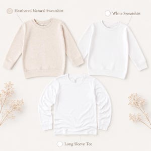 May include: Three plain tops are displayed on a white background. The top left is a heathered natural sweatshirt, the top right is a white sweatshirt, and the bottom is a white long sleeve tee. The garments are laid flat, ready for customisation.
