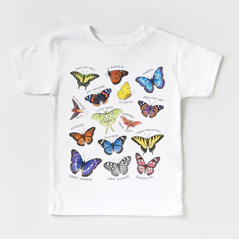 May include: White t-shirt featuring a colorful illustration of various butterfly species, including Monarch, Morpho, and Swallowtail. Each butterfly is labeled with its name in black text. A whimsical design for nature lovers.