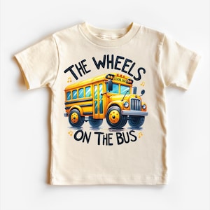 May include: A beige short-sleeved t-shirt with a yellow school bus illustration and the text "THE WHEELS ON THE BUS".