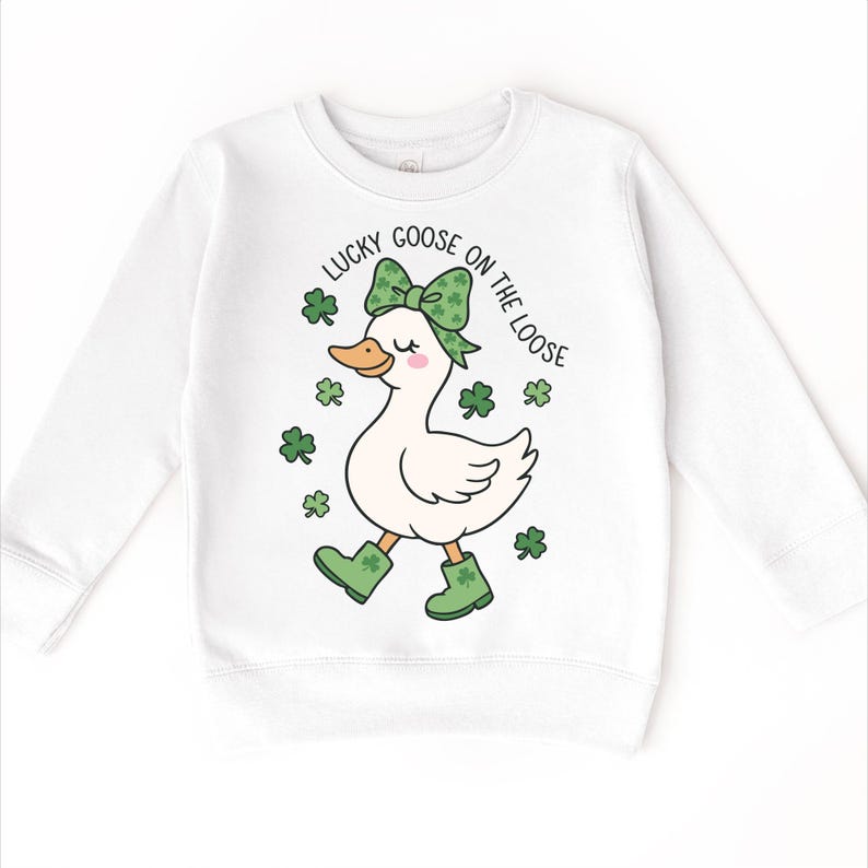 May include: White sweatshirt featuring a cartoon goose wearing a green bow, boots, and surrounded by shamrocks. The text "Lucky Goose on the Loose" is printed above the goose. The design is perfect for St. Patrick's Day.