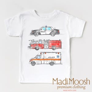 May include: White t-shirt with a watercolor illustration of a police car, fire truck, and ambulance. The text "Madi Moosh premium clothing" and "Made with Love" are printed on the bottom of the shirt.