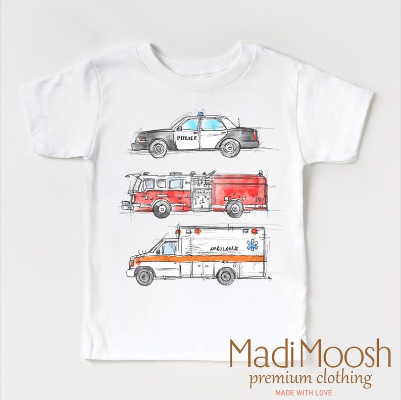 May include: White t-shirt with a watercolor illustration of a police car, fire truck, and ambulance. The text "Madi Moosh premium clothing" and "Made with Love" are printed on the bottom of the shirt.