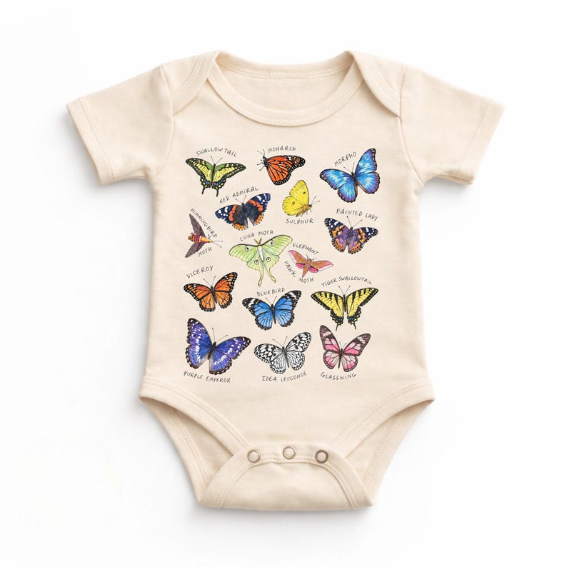 May include: Cream-colored baby onesie featuring a colorful butterfly graphic. The design includes various butterfly illustrations with their names, such as Monarch, Painted Lady, and Swallowtail. The onesie has short sleeves and snap closures.
