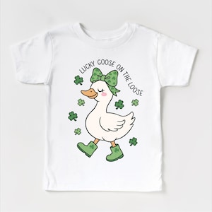 May include: White t-shirt featuring a cartoon goose with a green bow, boots, and shamrocks. The text "LUCKY GOOSE ON THE LOOSE" is arched above the goose. The design is perfect for St. Patrick's Day.