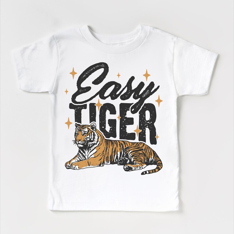 Op de afbeelding: Wit T-shirt met een zwarte en gouden afbeelding met de tekst "Easy Tiger" en een tijgerillustratie.