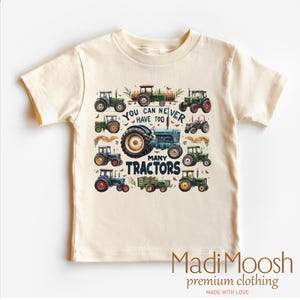 May include: A light beige toddler t-shirt with a graphic print of tractors and the text "You can never have too many tractors".