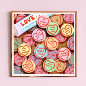 May include: A close-up of a collection of heart-shaped candies with various colors and messages about love. The candies are arranged in a random pattern and include phrases like "Love", "Never Fails", "Is Not Arrogant", and "Protects & Trusts".