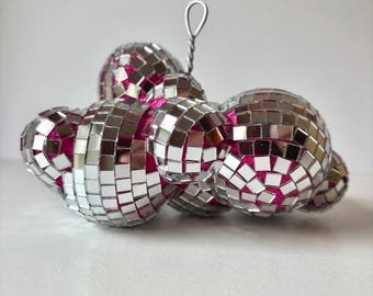 May include: A cluster of silver disco balls with pink centers, connected by a silver wire.