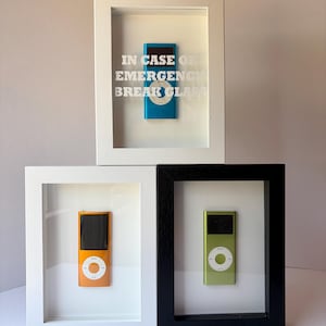 May include: Three framed iPods in white, black, and white frames. The top frame contains a blue iPod with the text "IN CASE OF EMERGENCY BREAK GLASS". The other frames hold orange and green iPods.