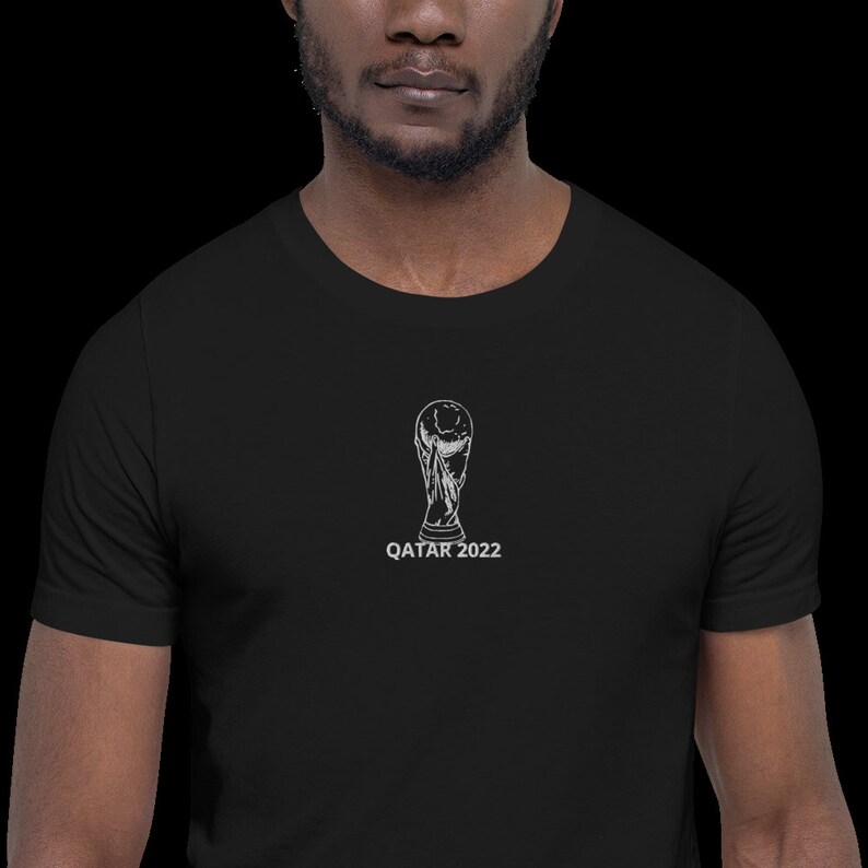 May include: A black t-shirt with a white graphic of the FIFA World Cup trophy and the text "QATAR 2022".