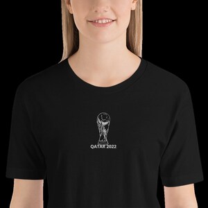 May include: Black t-shirt with a white graphic of the FIFA World Cup trophy and the text "QATAR 2022".