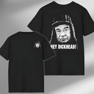 May include: Black t-shirts with a white graphic print. One shirt features a face with the text "HEY DICKHEAD!". The other shirt has a small face graphic on the chest. The shirts are short-sleeved.