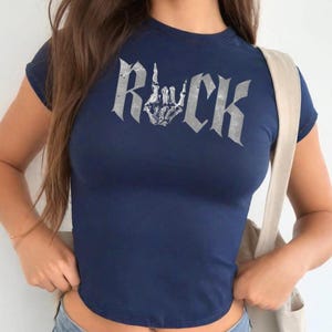 A woman wearing a navy blue t-shirt with the word "Rock" printed on it.