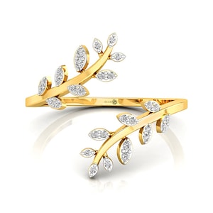 May include: A gold open-style ring featuring two branching leaf designs extending from the band. Each leaf is encrusted with small, clear, sparkling stones. The inner band of the ring is engraved with the text CEUM.