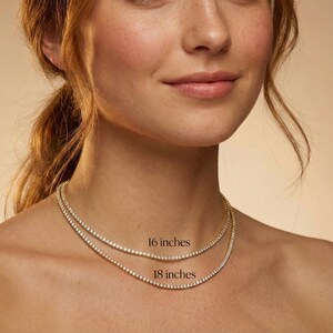 May include: Two delicate gold necklaces with sparkling clear stones are displayed. The top necklace is 16 inches long, and the bottom necklace is 18 inches long. The necklaces are worn around the neck.