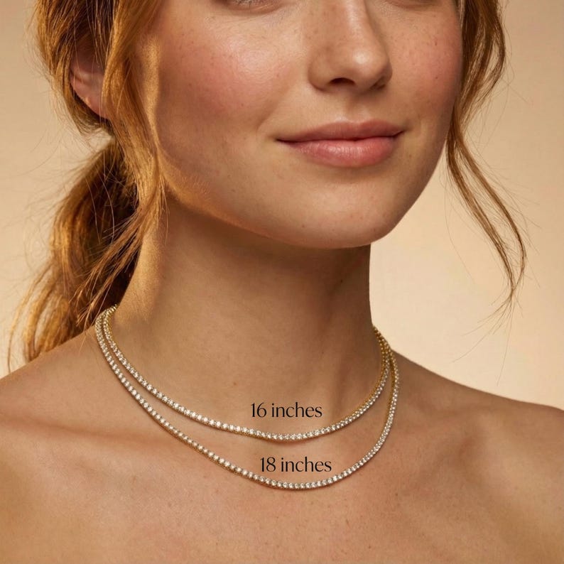 May include: Two delicate gold necklaces with sparkling clear stones are displayed. The top necklace is 16 inches long, and the bottom necklace is 18 inches long. The necklaces are worn around the neck.