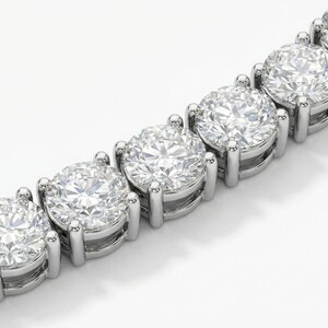 May include: Close-up of a diamond tennis bracelet. The bracelet features a series of large, round-cut diamonds set in a silver or platinum metal. The diamonds are clear and sparkling, reflecting light. The setting is a classic prong style.