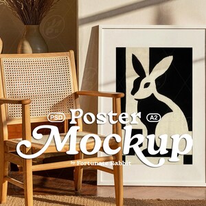 May include: A framed A2 poster mockup featuring a black and white rabbit design. A wooden chair with a woven back and armrests is positioned in front of the poster. The words "Poster Mockup" are displayed in a stylized font.