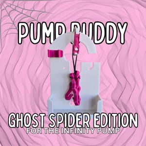 Könnte beinhalten: Ein weißes Kunststoffgerät mit dem Text "PUMP BUDDY" und "GHOST SPIDER EDITION" in einem rosa-weißen Farbschema. Das Gerät hat einen rosa Akzent und ein rosa Zubehör, das daran hängt. Der Hintergrund ist rosa.