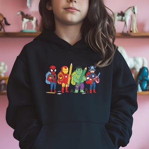 Puede incluir: Sudadera con capucha negra con un gr&aacute;fico colorido de superh&eacute;roes de Marvel como estudiantes, cada uno sosteniendo un l&aacute;piz o &uacute;tiles escolares. Los personajes incluyen a Spider-Man, Iron Man, Hulk y Capit&aacute;n Am&eacute;rica. Un dise&ntilde;o divertido de los Vengadores.