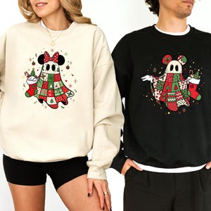Peut inclure: Un sweat-shirt beige et un sweat-shirt noir, chacun arborant un motif de fantôme portant des oreilles de souris et une couverture style patchwork aux motifs de Noël rouges et verts, incluant des sapins, des chaussettes et des boules.