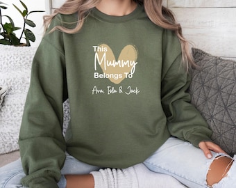 Könnte beinhalten: Ein olivgrünes Sweatshirt mit Rundhalsausschnitt, einem beigen Herzmotiv und weißem Text, der "This Mummy Belongs To" lautet, gefolgt von den Namen "Ava, Isla & Jack" in weißer Schreibschrift auf der Brust.