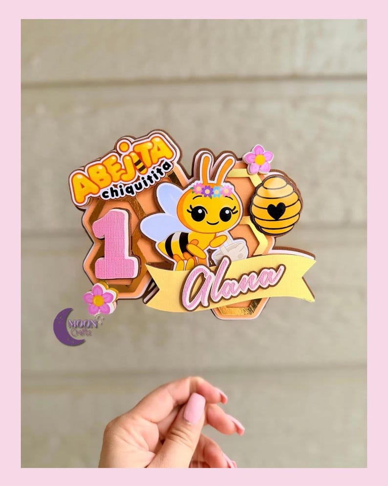 Puede incluir: Adorno para tarta con una abeja de dibujos animados, el texto "Abejita Chiquitita" y el nombre "Alana". El dise&ntilde;o incluye un n&uacute;mero 1, flores y un fondo de panal. El adorno es en tonos rosa, amarillo y dorado.