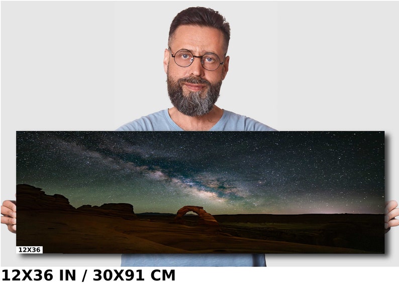 May include: A night sky photograph featuring the Milky Way galaxy over a desert landscape with a natural sandstone arch. The image is 12x36 inches or 30x91 centimeters.