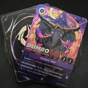 May include: A collectible card featuring an illustration of an elephant wearing a wizard hat, with the name "DUMBO" and the text "Ninth Wonder of the Universe." The card has a purple and pink background and includes game-related text.