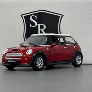 May include: Red Mini Cooper S model car with a white roof. The car has a black grille and black wheels.
