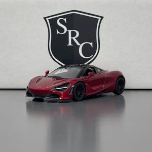 Puede incluir: Un modelo de coche deportivo rojo con ruedas negras y techo negro. El coche está delante de un fondo blanco con un logotipo en blanco y negro que dice "SRC".
