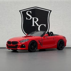 Puede incluir: Un modelo de coche de juguete rojo convertible BMW Z4.
