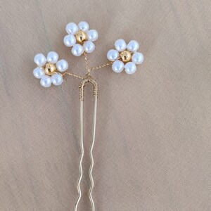 May include: Gold hair clip with three white pearl flower accents.