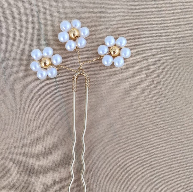 May include: Gold hair clip with three white pearl flower accents.