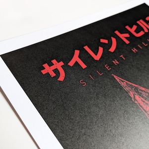 Silent Hill 2 Game Poster - Character set on a black background with a mixture of Japanese and English text in red. Available in A5, A4, A3 & A2. This close up photo shows the detail of the Japanese and English title text.