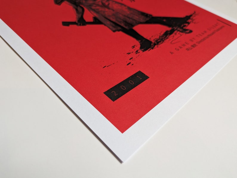 Silent Hill 2 Game Poster - Character set on a red background with a mixture of Japanese and English text in black. Available in A5, A4, A3 & A2. This close up photo shows the detail of the year the game was published.