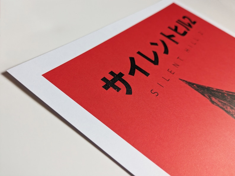 Silent Hill 2 Game Poster - Character set on a red background with a mixture of Japanese and English text in black. Available in A5, A4, A3 & A2. This close up photo shows the detail of the Japanese text.