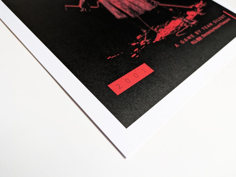 Silent Hill 2 Game Poster - Character set on a black background with a mixture of Japanese and English text in red. Available in A5, A4, A3 & A2. This close up photo shows the detail of the year the game was published.