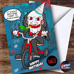 Könnte beinhalten: Eine Geburtstagskarte mit einer Comicfigur aus dem Saw-Film-Franchise, die einen Partyhut trägt und ein Dreirad fährt. Die Karte hat einen blauen Hintergrund mit dem Text "Es ist dein Geburtstag! Ich möchte ein Spiel spielen!" und "Happy Birthday" mit dem Wort "SAW" in Rot.