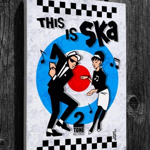 May include: A white canvas print with a black and white chequered border. The print features a blue and red target with two figures dancing. The text "This is Ska" is written in black letters. The text "2 Tone Records" is written in black letters below the target.