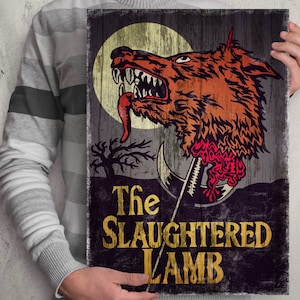 Könnte beinhalten: Holzschild mit einer Vintage-Illustration eines Wolfskopfes, einem Vollmond und dem Text "The Slaughtered Lamb" in Gold. Das Kunstwerk zeigt einen Wolfskopf mit freiliegenden Zähnen und Zunge.
