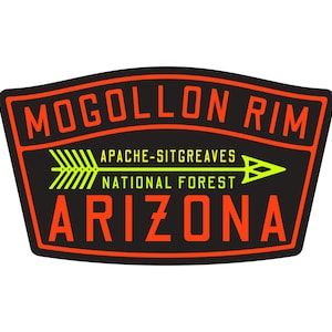May include: A rectangular patch with a black background and an orange border. The text "Mogollon Rim" is arched across the top. Below, a yellow arrow points right, with the words "Apache-Sitgreaves National Forest" and "Arizona" in orange.