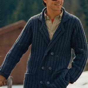 Op de afbeelding: Een marineblauwe, dubbelknoopgebreide jas met een reverskraag en twee rijen knopen. De jas heeft twee voorzakken en wordt gedragen over een lichtgekleurd overhemd met kraag. De afbeelding bevat ook de tekst "33 MADISON".