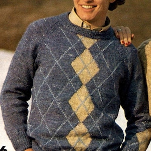 Könnte beinhalten: Ein blauer Argyle-Pullover mit beigem Rautenmuster. Der Pullover hat einen Rundhalsausschnitt und lange Ärmel. Die Person trägt darunter ein hellgelbes Hemd mit Kragen.