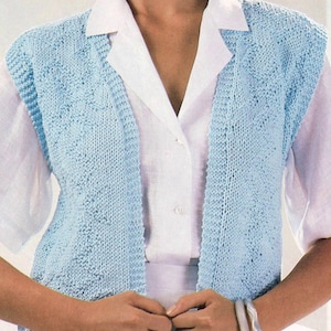May include: A light blue knitted vest with a textured pattern, worn over a white collared shirt. The vest has a V-neck and a sleeveless design. The image shows a close-up of the vest and shirt.